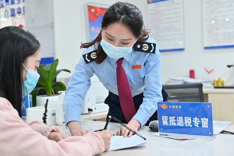 水城區(qū)稅務(wù)局窗口工作人員正在輔導(dǎo)納稅人填寫資料。（張定國攝）.jpg